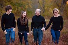 three adults and one child are standing in the tall grass with their hands on each other's hips