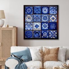 a blue and white tile wall hanging above a couch in a living room with pillows