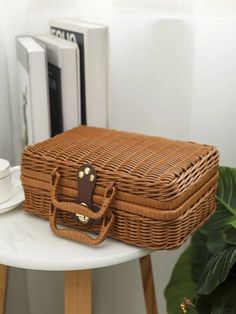 a brown wicker bag sitting on top of a white table next to a potted plant