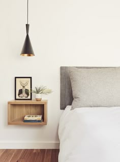 a bed with a wooden shelf next to it and a framed photograph on the wall