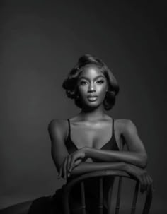 a black and white photo of a woman in a bathing suit sitting on a chair