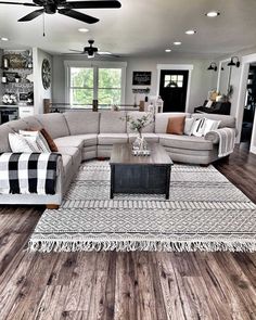 a living room filled with furniture on top of a hard wood floor covered in rugs