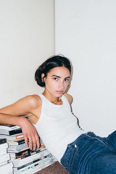 a woman sitting on the floor next to a pile of books