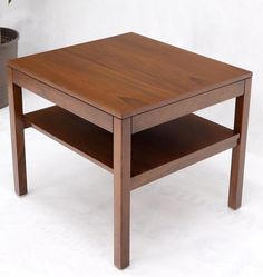 a wooden table sitting next to a potted plant on top of a white floor