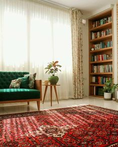 a green couch sitting in front of a window next to a book shelf filled with books