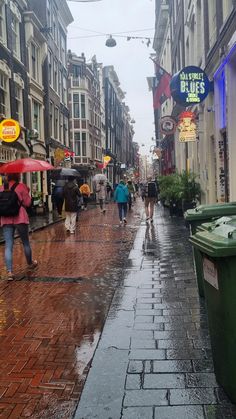 people walking down the street with umbrellas on a rainy day