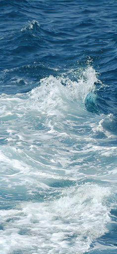 a person riding a surfboard on top of a wave in the ocean with blue water