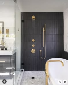 a black and gold bathroom with a walk in shower next to a white bathtub