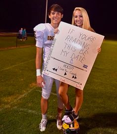 a man and woman posing for a photo while holding a sign