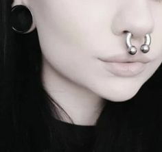 a woman with black hair and piercings on her nose