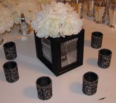 there are many candles and vases on the table with white flowers in front of them