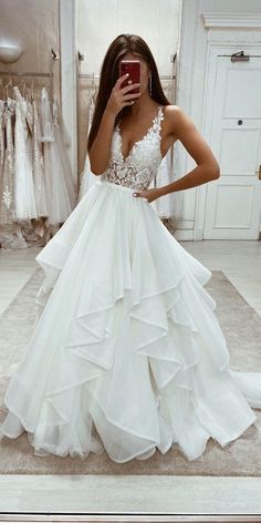 a woman taking a selfie while wearing a wedding dress in front of a mirror