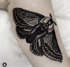 a black and white butterfly tattoo on the left arm, it looks like an insect