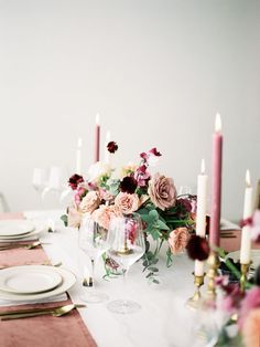 the table is set with candles, plates and napkins for an elegant dinner party