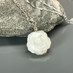 "Mother of Pearl Rose Flower Pendant Necklace- Carved White MOP  Introducing our exquisite Mother of Pearl Rose Flower Pendant Necklace, a timeless piece of jewelry that embodies elegance and grace. This pendant showcases a meticulously carved white Mother of Pearl rose flower, symbolizing beauty, love, and femininity. Crafted with utmost precision and attention to detail, the delicate petals of the rose are intricately carved, capturing the natural allure of the flower. The lustrous iridescence White Flower-shaped Jewelry For Formal Occasions, Formal White Flower-shaped Jewelry, White Petal-shaped Jewelry With Flower Charm, White Flower Charm Pendant Jewelry, White Flower Pendant Jewelry Gift For Her, Elegant Sterling Silver Jewelry With Rose Design, Delicate Formal Necklaces For Mother's Day, Formal White Jewelry With Rose Design, Formal White Rose Design Jewelry