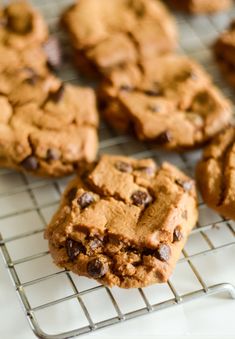 chocolate chip cookies cooling on a wire rack, with one cookie broken in the middle