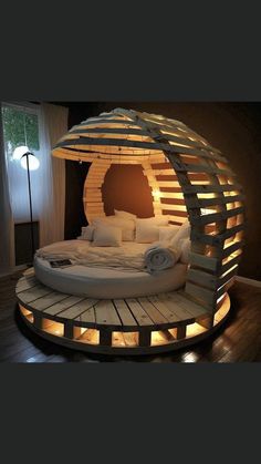 a circular bed made out of pallets with lights around it and pillows on the bottom