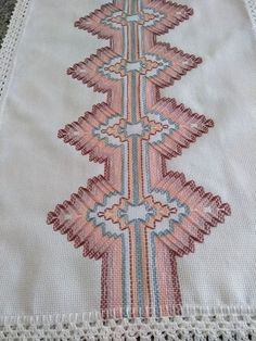 an embroidered table runner with pink and blue designs