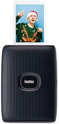 an instax photo frame is placed on top of a black suitcase with the image of a man in santa's hat