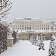 snow covered trees and statues in front of a large building