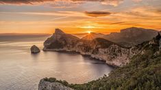 the sun is setting over an island in the ocean