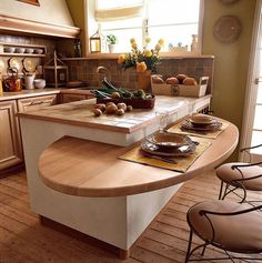 a kitchen island with plates and bowls on it in the middle of a wooden floor