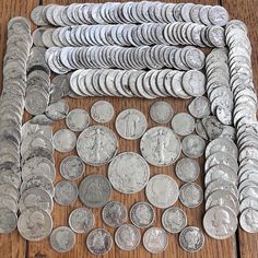 a pile of silver coins sitting on top of a wooden table next to each other