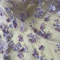 purple and white flowers are scattered on the sheered fabric, which is draped over it