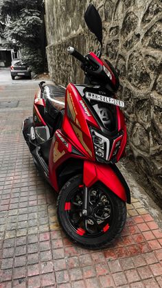 a red motorcycle parked next to a stone wall