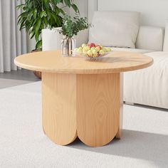 a wooden table with fruit on it in front of a white couch and potted plant