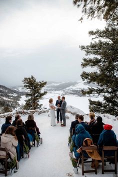 a bride and groom standing at the end of their wedding ceremony on top of a snowy mountain