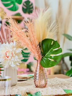 two vases filled with flowers on top of a table covered in plates and napkins