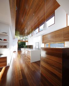 an open kitchen and dining area with wood flooring, white counter tops and wooden ceiling