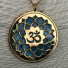 "Om in 24 carat gold on 925 silver and blue mother of pearl backdrop. Om is one of the most important spiritual symbols, a sacred sound in Indian religions, found also in some chapters of the Veda. It has variously been associated with concepts of \"cosmic sound\" that celebrates the creative powers of the Universe. Its sound is made up of three syllabes (A-U-M): wakefulness / darkness / present, dream / unconscious / past, deep sleep / future truth. In the jewel The five curves shaping the Om s Spiritual Hallmarked Necklaces, Spiritual Blue Jewelry For Festivals, Spiritual Blue Medallion Necklaces, Blue Medallion Necklace For Spiritual Style, Blue Medallion Spiritual Necklaces, Blue Spiritual Locket Jewelry, Spiritual Gold Necklace With Mother Of Pearl, Blue Hallmarked Spiritual Necklaces, Pearl Backdrop