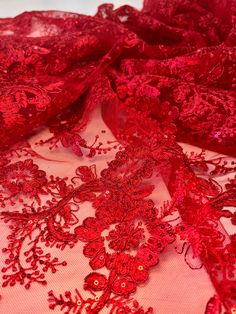 red lace fabric with flowers and leaves on the bottom, as well as sequins