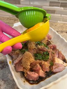 a person in pink gloves is scooping food out of a bowl with a green strainer