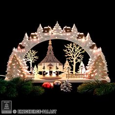 a lighted christmas scene with trees and buildings in the background, surrounded by white lights