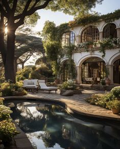 an outdoor swimming pool surrounded by trees and bushes with sun shining through the windows on the building