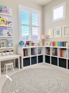 a child's playroom with bookshelves and toys on the floor in front of windows