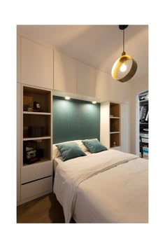 a white bed sitting under a light next to a book shelf