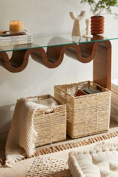 two wicker baskets under a glass table with books on it and vases in the background