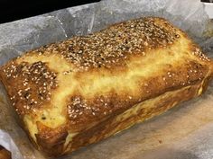 a loaf of bread sitting on top of a piece of wax paper covered in sesame seeds