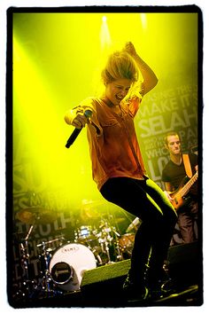 a woman standing on top of a stage holding a microphone in front of her head