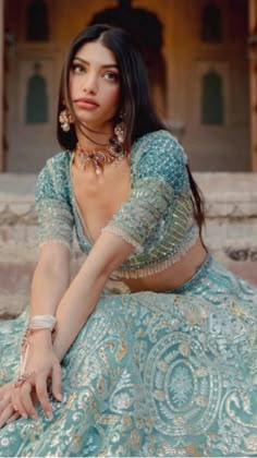 a woman in a blue dress sitting on some steps