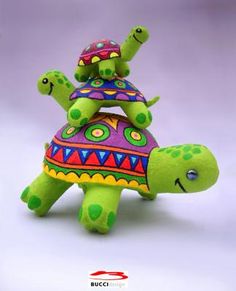 a small stuffed turtle with a colorful hat on its head and arms, sitting in front of a white background