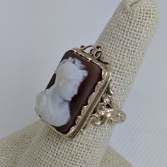 This gorgeous vintage cameo ring is beautifully crafted in a solid 14k gold frame with details at every angle. The victorian style is likely a 1930-1950s creation. In the center is a carved shell cameo of a Roman soldier. The cameo is in excellent condition and the sturdy ring measures approximately 26.45mm tall (including gold filigree fame) x 17.37mm wide. The ring is currently a ring size 7.5 but can be resized by your trusted local jeweler. A bold statement ring for men and women who love an Antique Cameo Ring Collectible, Elegant Cameo Rings For Collectors, Antique Carved Collectible Ring, Collectible Art Deco Cameo Jewelry, Antique Cameo Ring Jewelry, Vintage 14k Gold Cameo Rings, Vintage 14k Gold Carved Ring, Cameo 14k Gold Rings For Collectors, Vintage Carved Rings For Formal Occasions