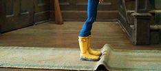 a woman in yellow rain boots is standing on the floor with her legs crossed and wearing blue jeans