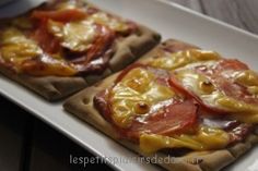 two square pizzas with tomatoes and cheese on them sitting on a white platter