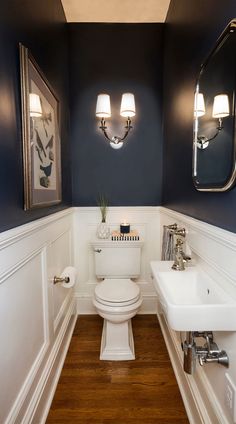 a white toilet sitting under two mirrors in a bathroom