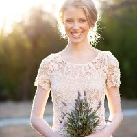 a woman holding a potted plant in her hands and smiling at the camera while standing outside